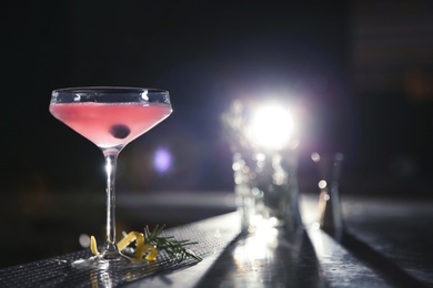 Photo of Glass of cosmopolitan martini cocktail on bar counter. Space for text