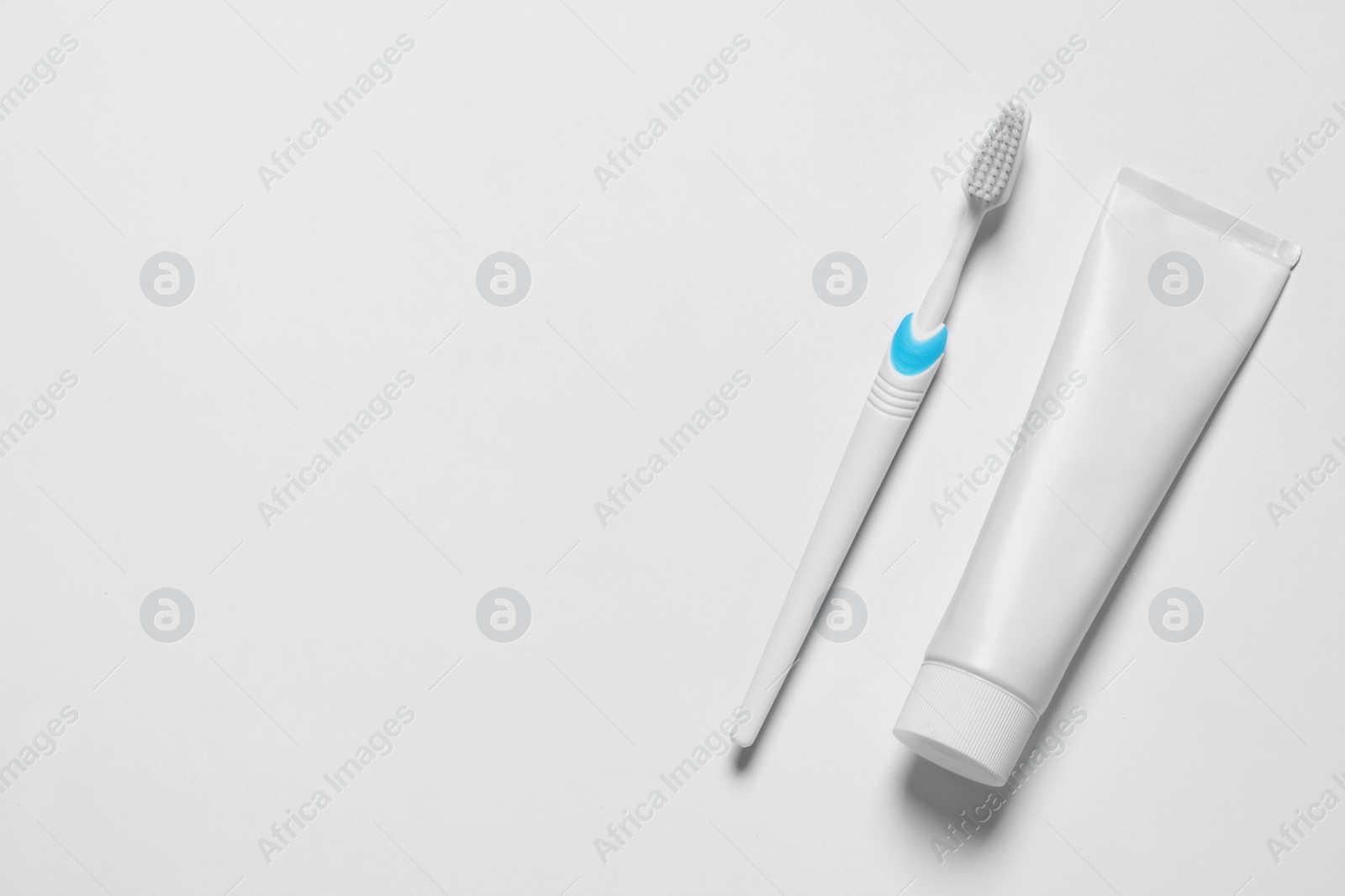 Photo of Plastic toothbrush and paste on white background, top view. Space for text