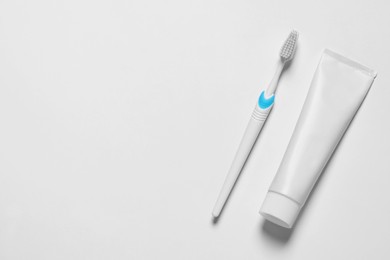 Plastic toothbrush and paste on white background, top view. Space for text