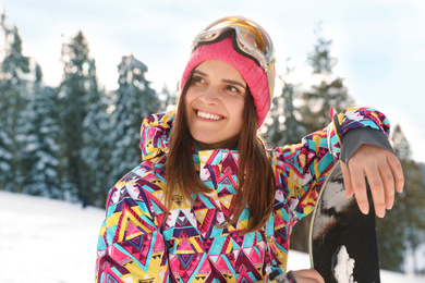 Photo of Young woman with snowboard on snowy slope. Winter vacation