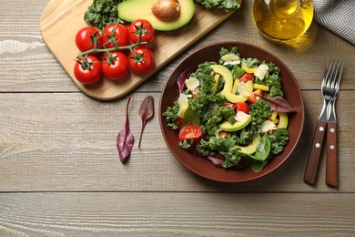 Photo of Tasty fresh kale salad on wooden table, flat lay