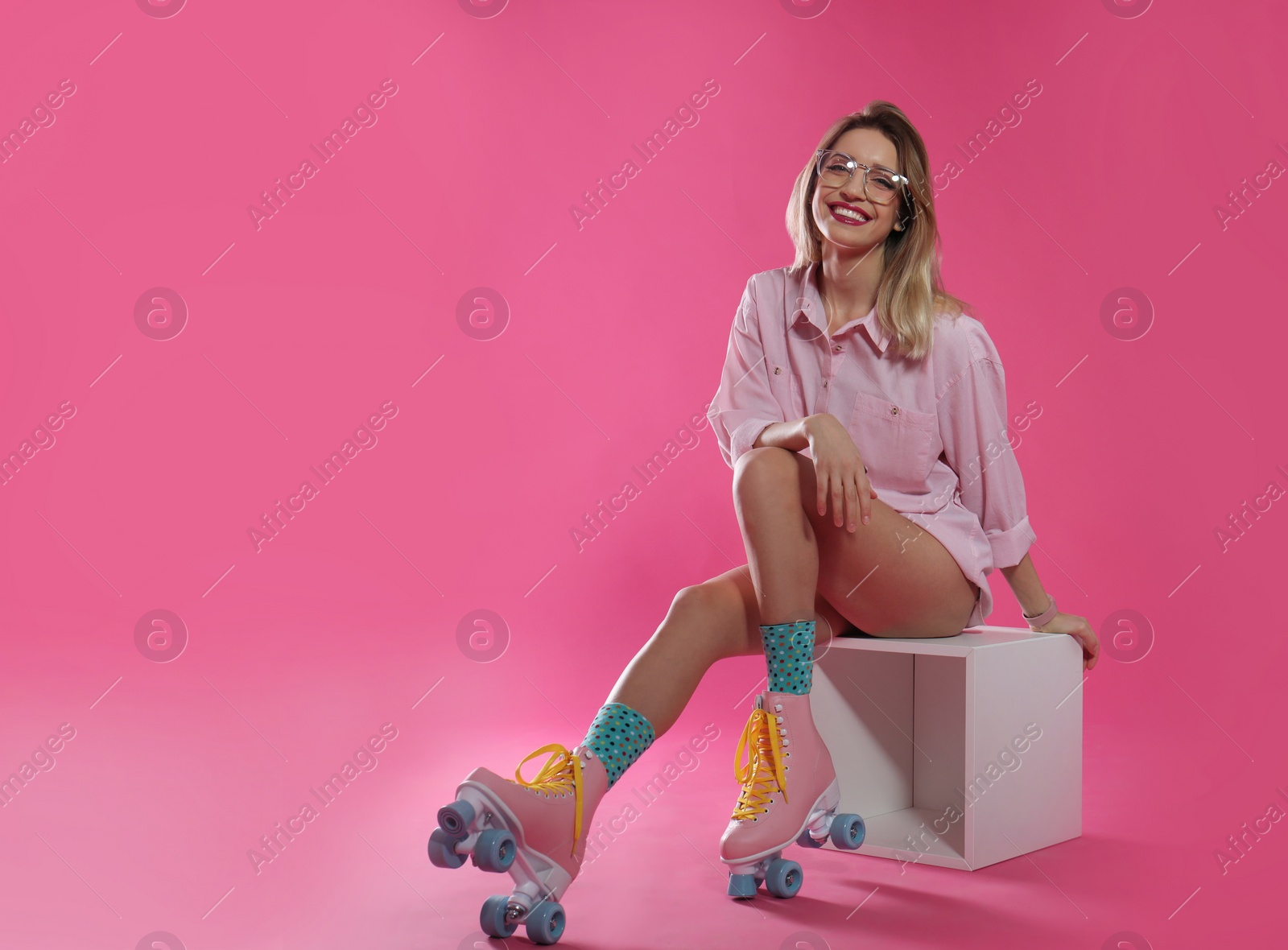 Photo of Young woman with retro roller skates on color background. Space for text