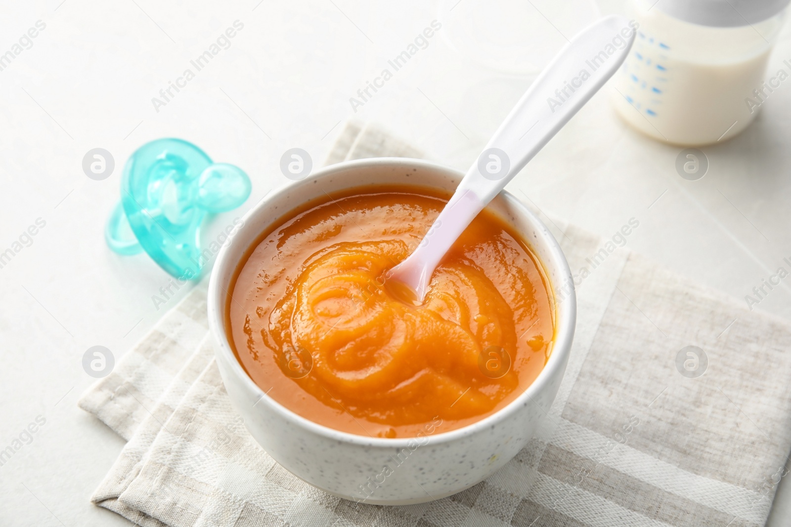 Photo of Bowl with healthy baby food on light table