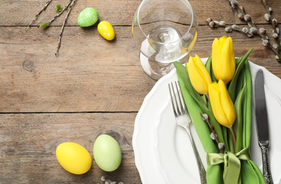 Festive Easter table setting with floral decor on wooden background, flat lay