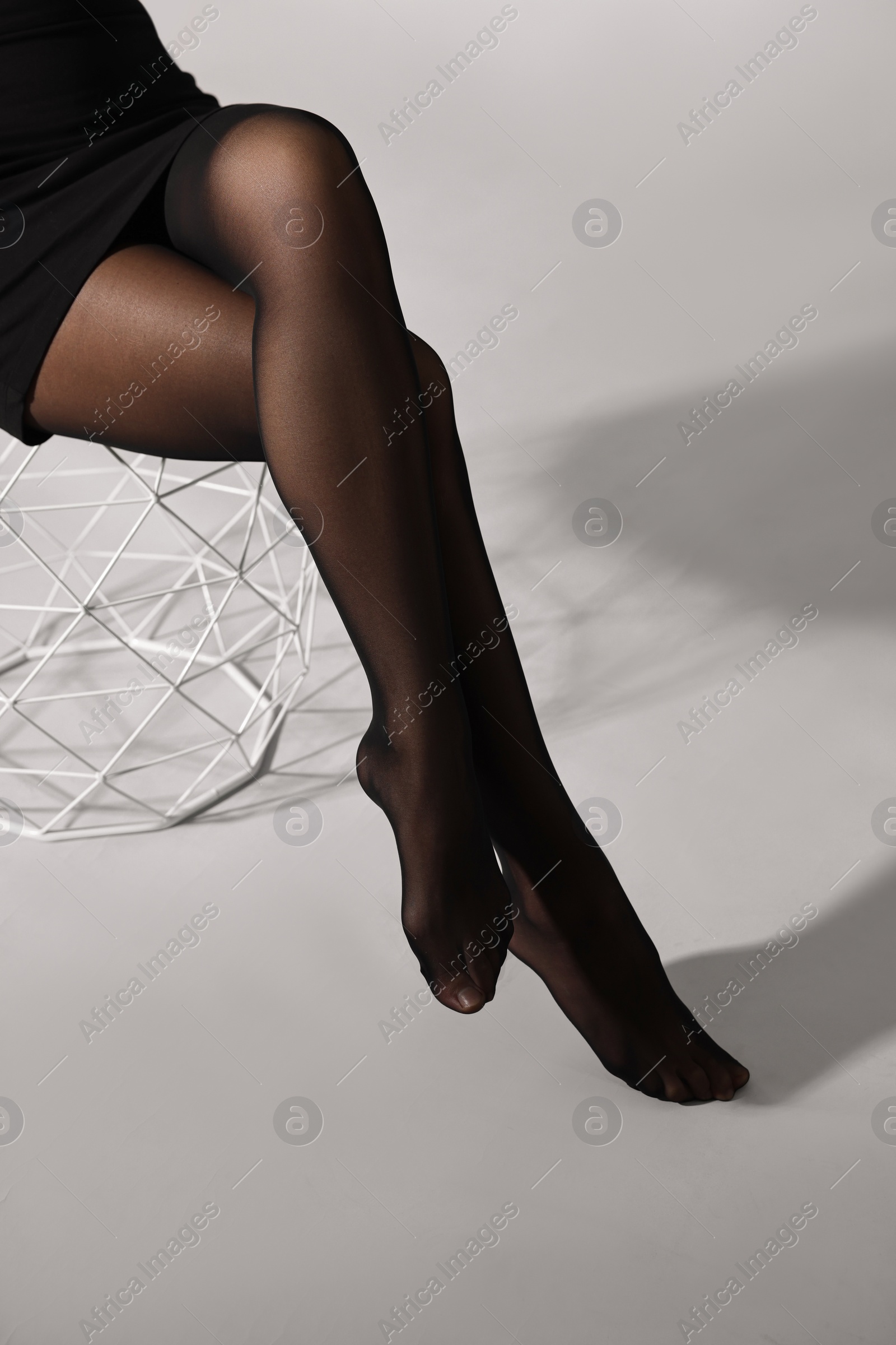 Photo of Woman with beautiful long legs wearing black tights on light background, closeup
