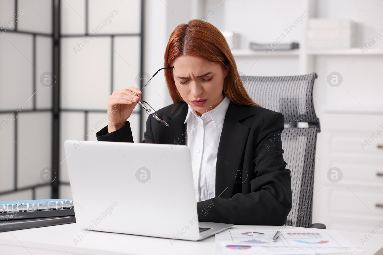 Photo of Woman suffering from headache at workplace in office