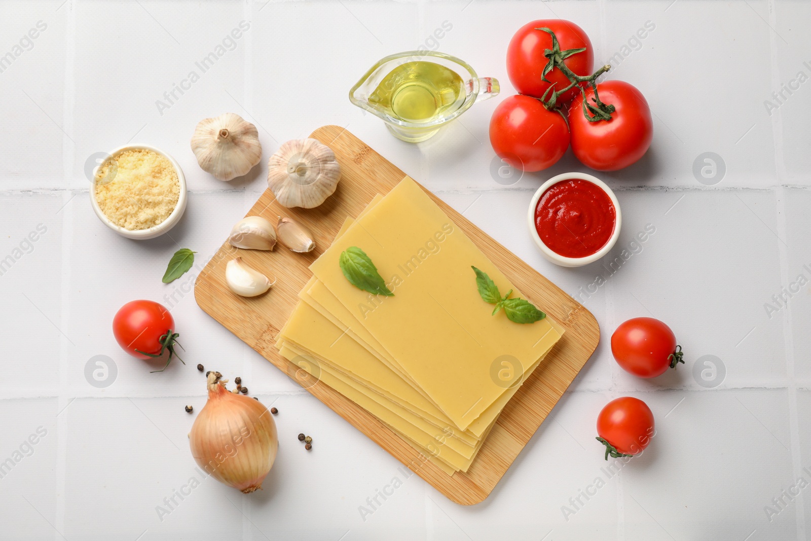 Photo of Ingredients for lasagna on white tiled table, flat lay
