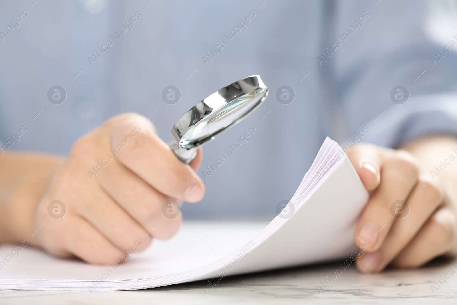 Photo of Woman using magnifying glass at table, closeup