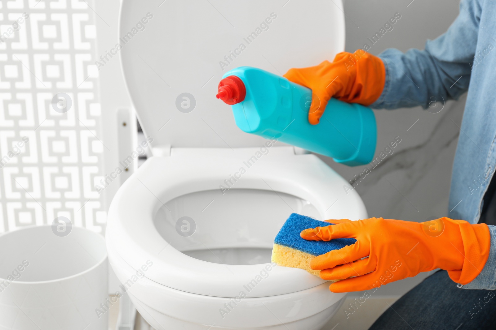 Photo of Woman cleaning toilet bowl in bathroom, closeup