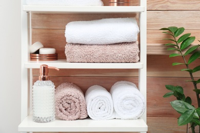 Photo of Towels, toiletries and soap dispenser on shelves in bathroom