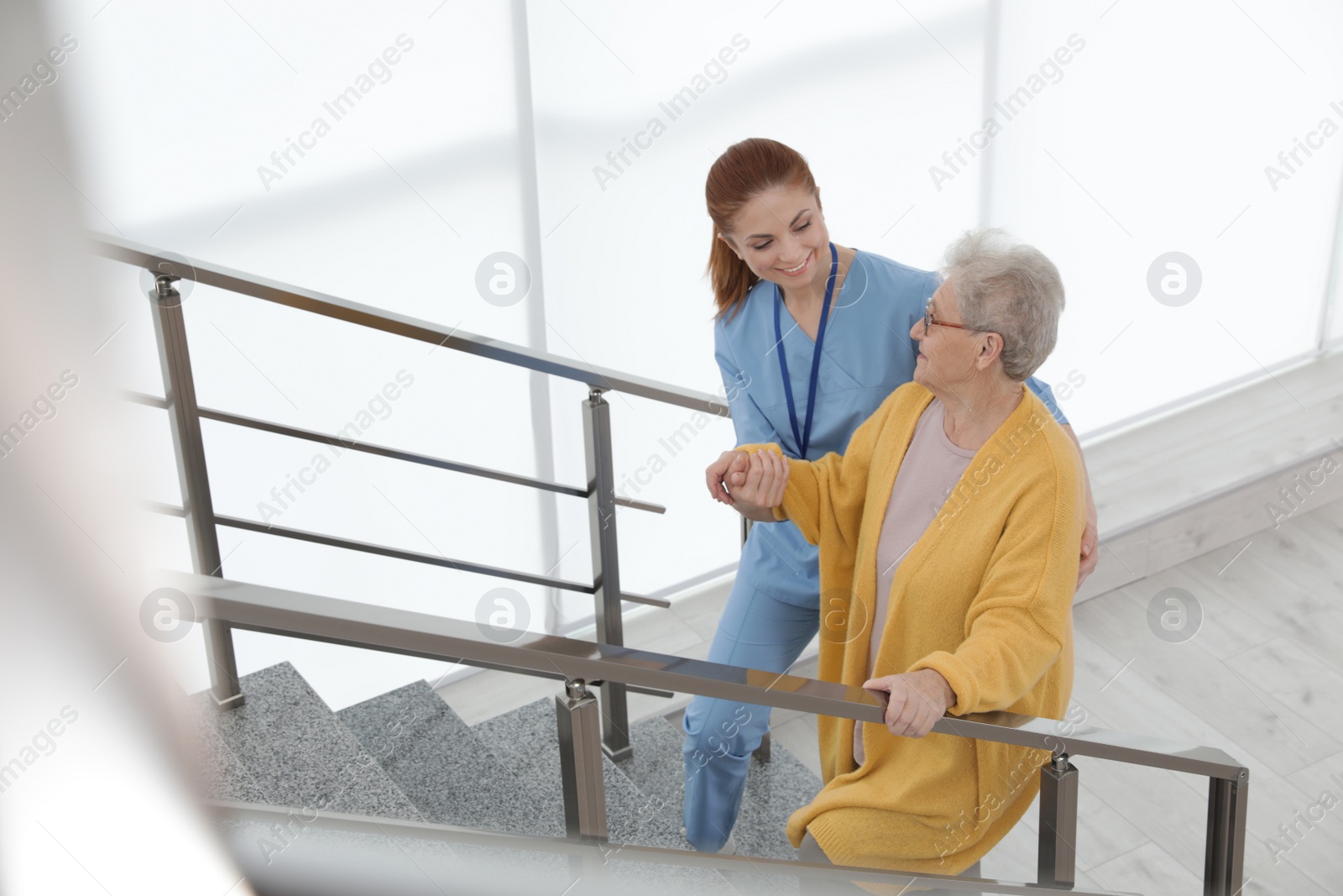 Photo of Nurse assisting senior woman to go up stairs at hospital