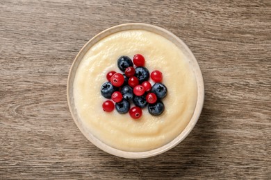 Delicious semolina pudding with berries on wooden table, top view