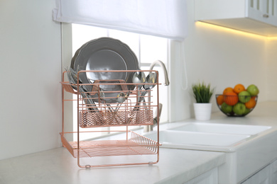 Clean dishes on drying rack in modern kitchen interior