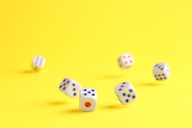 Photo of Many white game dices falling on yellow background