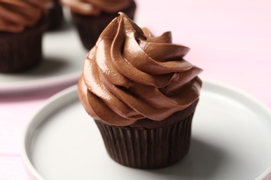 Photo of Delicious chocolate cupcake with cream on plate, closeup