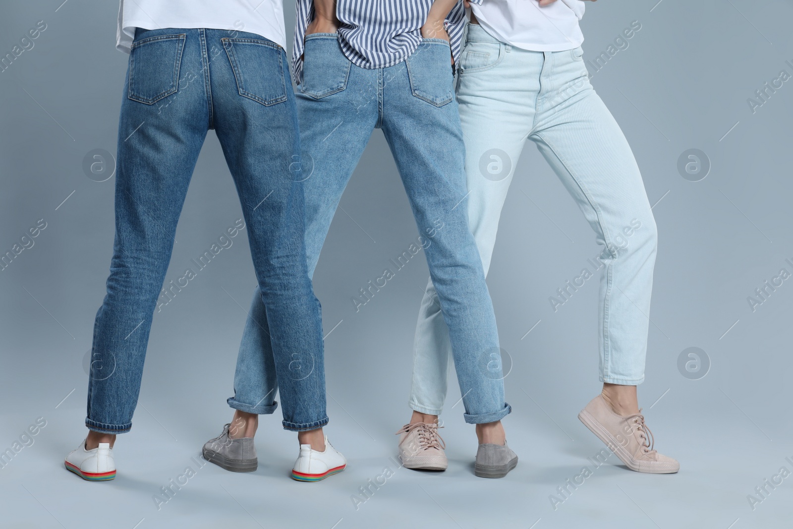 Photo of Group of young women in stylish jeans on grey background, closeup