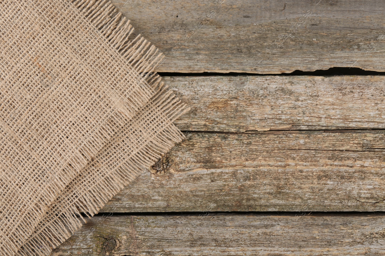 Photo of Piece of folded burlap fabric on wooden table, top view. Space for text