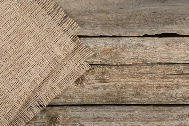 Piece of folded burlap fabric on wooden table, top view. Space for text