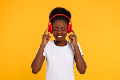 Photo of Young woman in headphones enjoying music on orange background