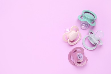 Photo of Flat lay composition with baby pacifiers on violet background. Space for text