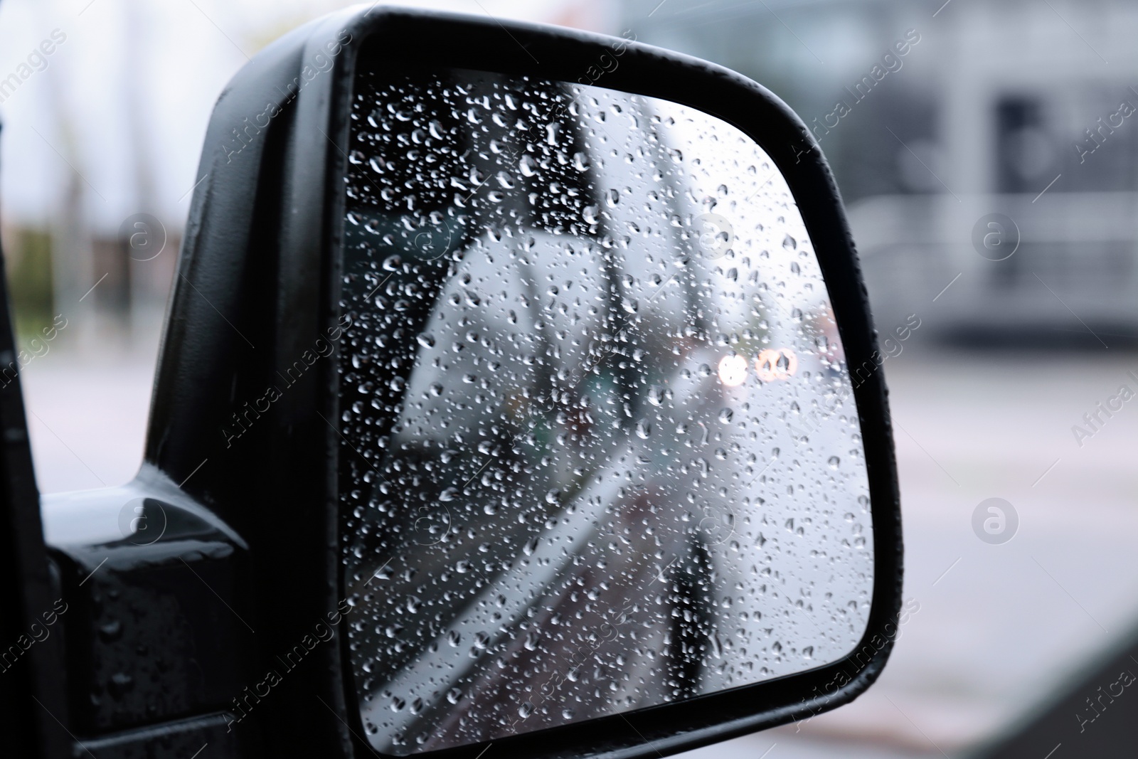 Photo of Closeup of car side rear view mirror with rain drops