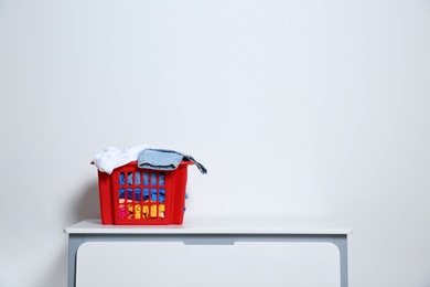 Photo of Laundry basket with dirty clothes on cabinet at white wall, space for text
