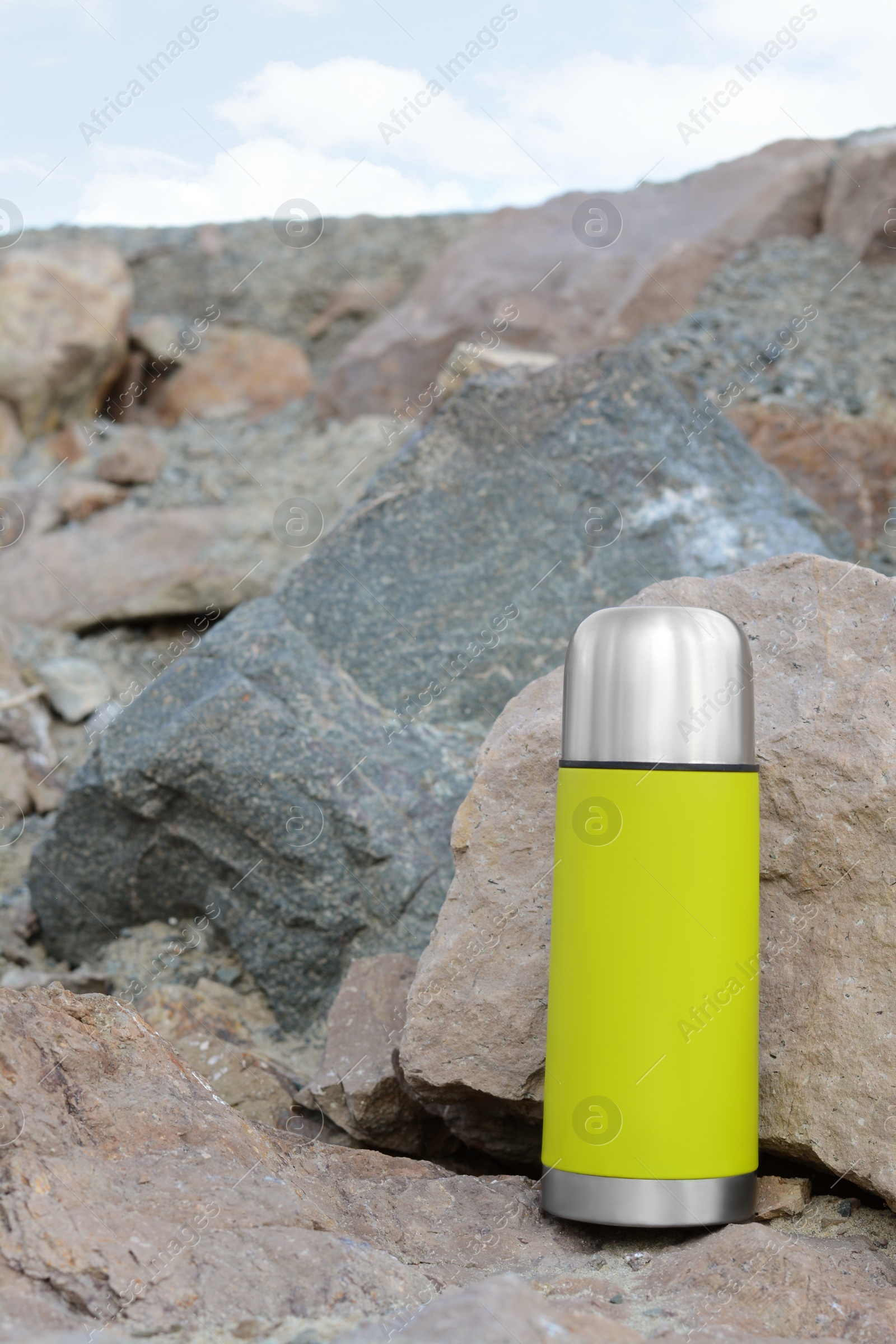 Photo of Metallic thermos with hot drink on stone outdoors, space for text