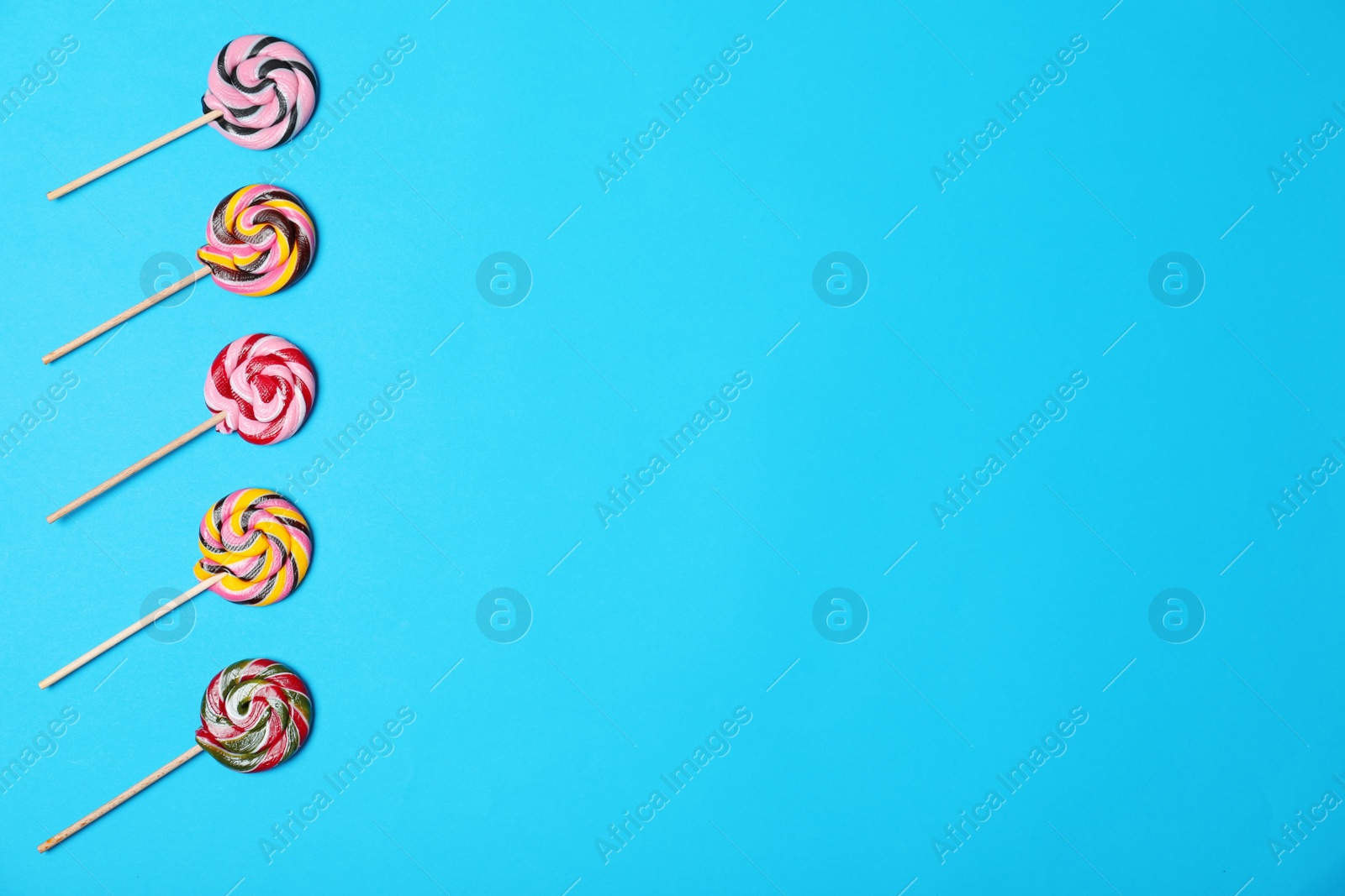 Photo of Bright yummy candies and space for text on color background, top view