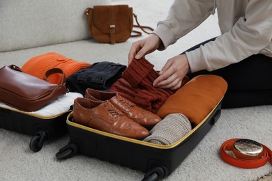 Photo of Woman packing suitcase for trip at home, closeup