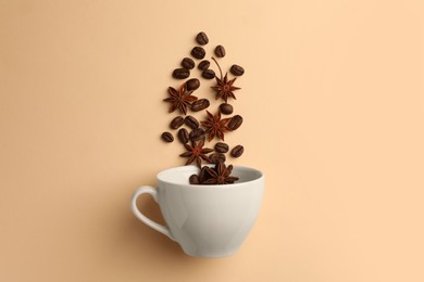 Photo of Coffee beans and anise stars falling into cup on beige background, flat lay