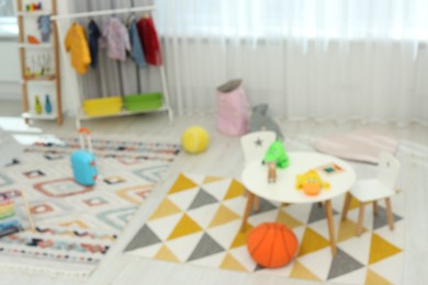 Photo of Blurred view of kid`s playroom with different toys and furniture. Stylish kindergarten interior
