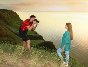 Photo of Male photographer taking picture of young woman with professional camera on green hill