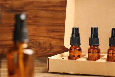 Photo of Bottles of oil in box on wooden table, closeup with space for text. Natural cosmetics
