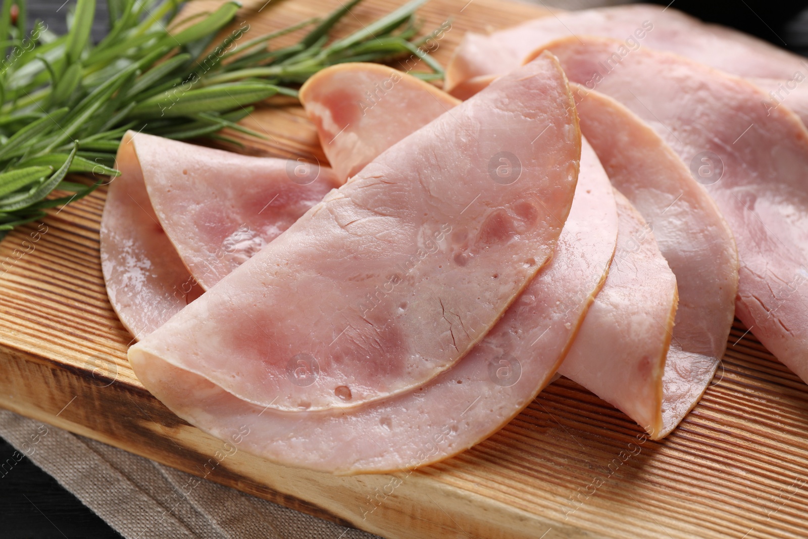 Photo of Slices of delicious ham with rosemary on table, closeup
