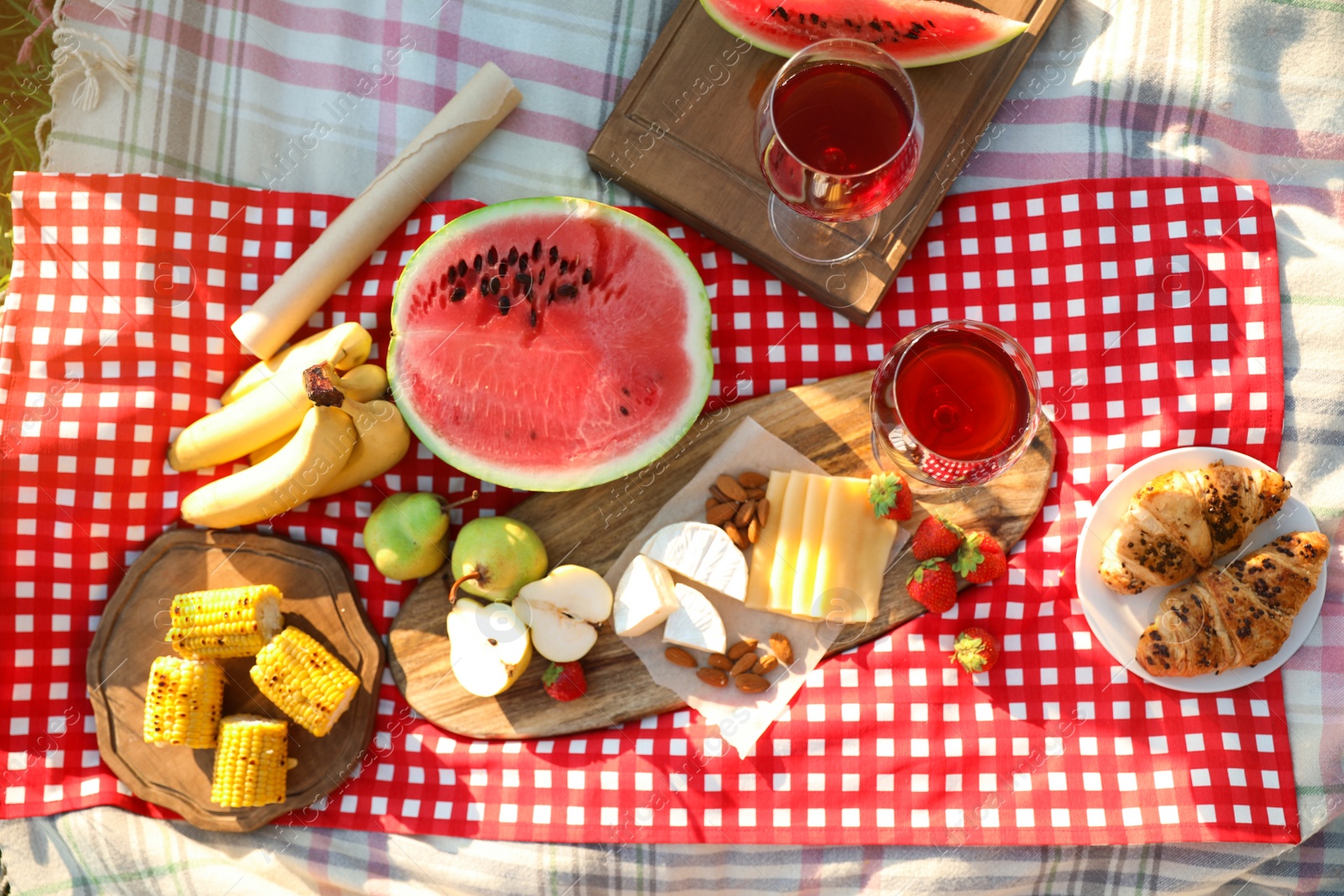 Photo of Picnic blanket with delicious food and drinks outdoors on sunny day, flat lay