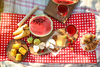 Photo of Picnic blanket with delicious food and drinks outdoors on sunny day, flat lay