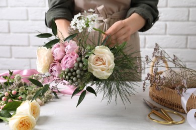 Photo of Florist making beautiful bouquet at white table, closeup