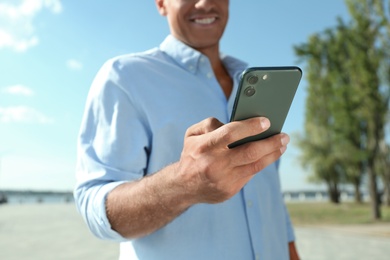 Man using modern mobile phone outdoors, closeup