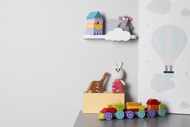 Beautiful poster and toys on table in baby room, space for text. Interior design