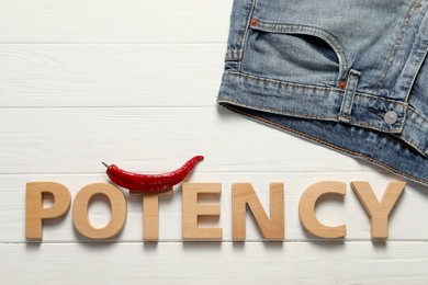 Photo of Word Potency made of letters, jeans and chili pepper on white wooden table, flat lay