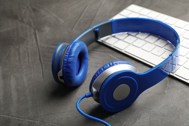 Photo of Modern headphones and computer keyboard on table