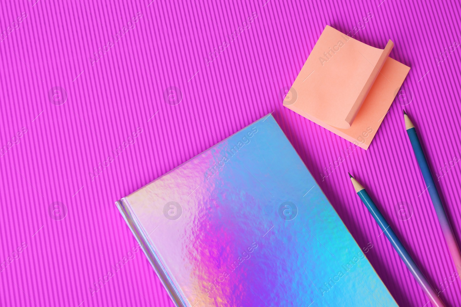 Photo of Beautiful notebook, sticky notes and pencils on color background