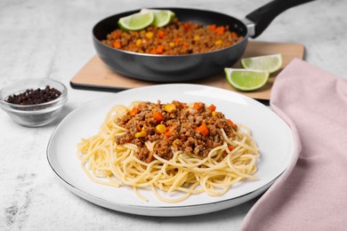 Tasty dish with fried minced meat, spaghetti, carrot and corn on served white textured table
