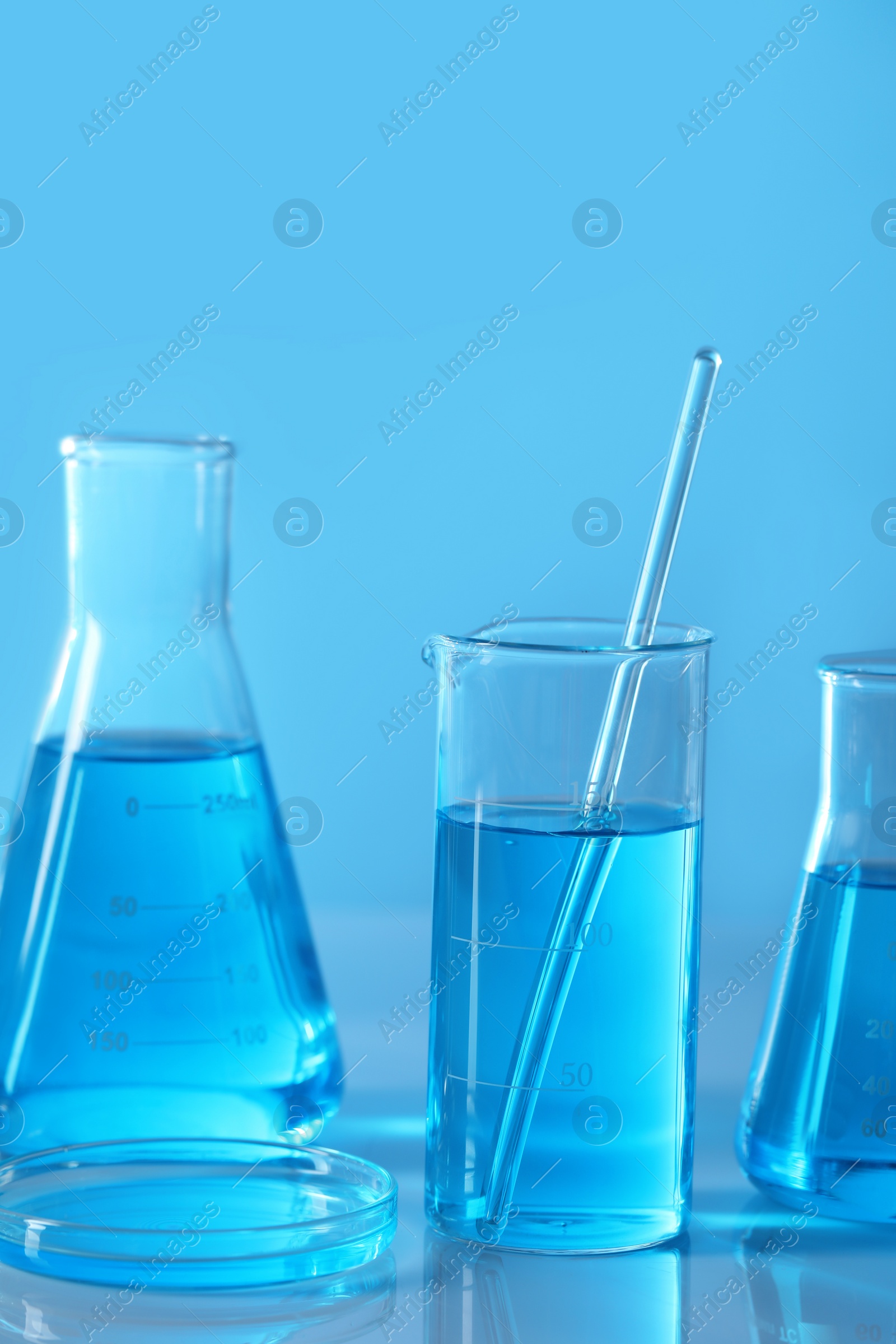 Photo of Different laboratory glassware with light blue liquid on table