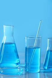 Photo of Different laboratory glassware with light blue liquid on table