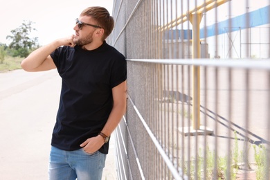 Photo of Young man wearing black t-shirt on street. Urban style