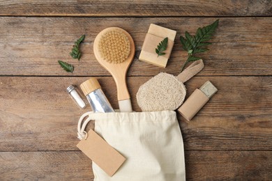 Photo of White cotton bag with eco friendly personal care products on wooden table, flat lay