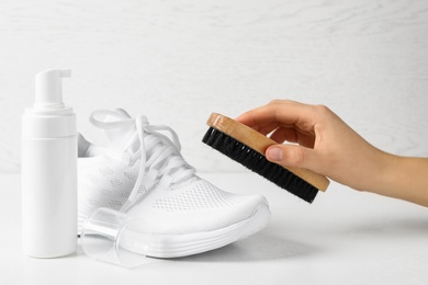 Woman cleaning stylish footwear on white background, closeup. Shoe care accessories