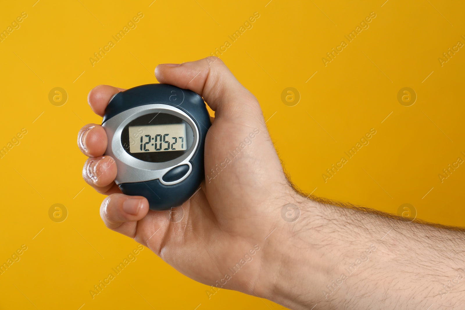 Photo of Man holding digital timer on yellow background, closeup