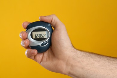 Man holding digital timer on yellow background, closeup